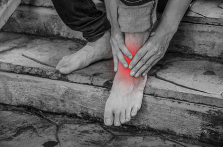 close-up young man feeling pain in his foot because leg cramps and ankles on stair, Have ankle pain, Health conceptの写真素材