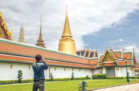 Young Asian traveling backpacker taking photos in Wat Phra Kaew in Bangkok, Thailandの写真素材