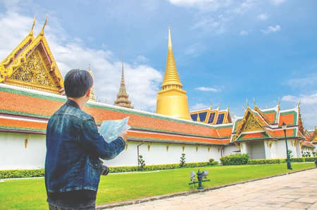 Young man traveler looking the Map in Wat Phra kaew at Bangkok Thailand. Traveling in Bangkok Thailandの写真素材