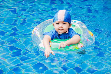 One little girls swimming in the pool with rubber ring, having fun in swimming pool.の写真素材