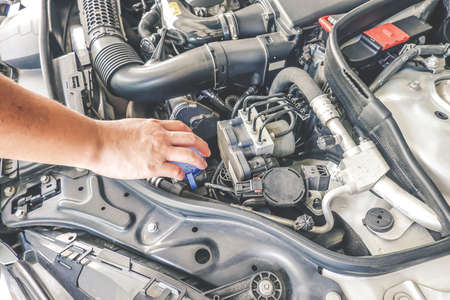 Hand of mechanic is repairing car engine working in garage, Repair service.