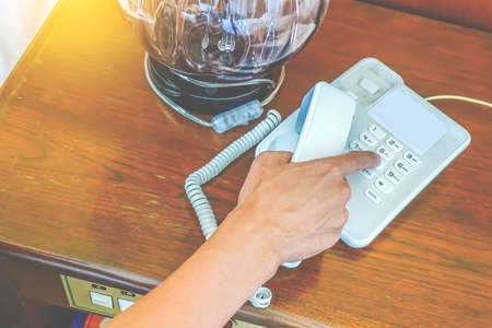 close-up partial view of hand man calling by phone in hotel roomの写真素材