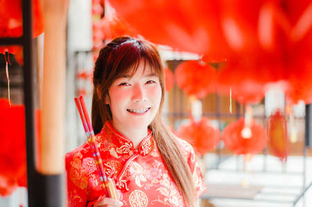 Portrait charming beautiful asian woman wear cheongsam dress up choose buy the incense, in the Chinese New Year. Festivities, New Year Celebrationの写真素材