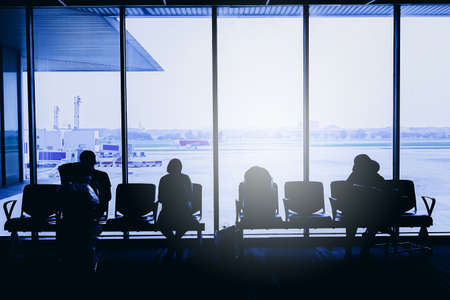 Silhouettes of business people traveling on airport; waiting at the plane boarding gates.の写真素材