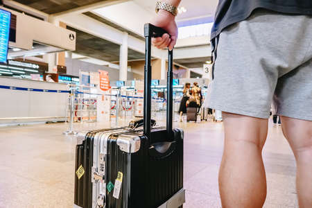 Man standing with luggage at airport. man looking at lounge looking at airplanes while waiting at boarding gate before departure.の写真素材