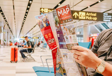 SINGAPORE - NOVEMBER  22, 2018: Travel vacation concept.Asian man in airport reading map while...
