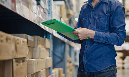Asian manager man doing stocktaking of products management in cardboard box on shelves in warehouse...