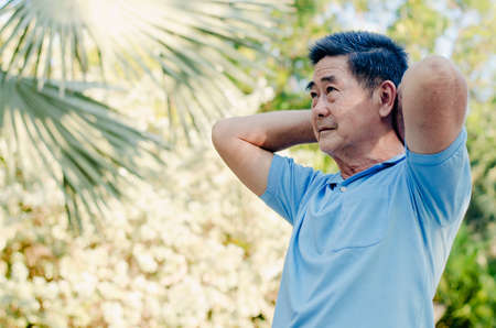 Happy senior man on a walk with armband doing stretching in green nature background.. Autumn nature.