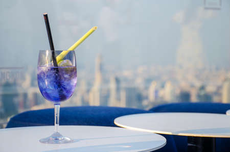 Iced cocktail glasses on the rooftop bar of Mahanakorn building in Bangkok with sunset backgroundの写真素材
