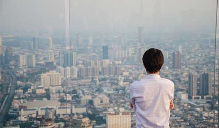 Man standing on roof and looking on city through the windowの写真素材