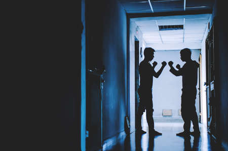 The silhouette of two young men angry conflict fighting with each other in  the old condo