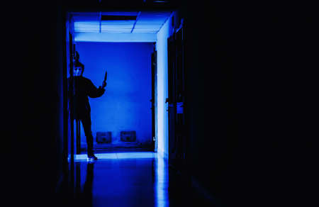 Murder, kill and people concept - Criminal or murderer wearing a mask in silhouette holding knife inside a condo at crime scene, Halloween concept.の写真素材