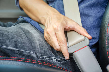Lack a seat belt before driving a car, Closeup of man fastening seat belt in car, Safety belt safety first.の写真素材