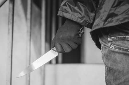 Bandit wearing a mask walking on stairs with a knife for the loot, focus is knifeの写真素材