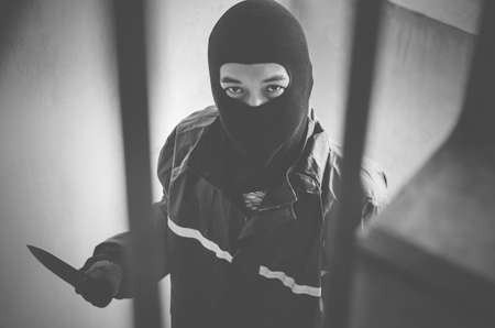 Bandit wearing a mask walking on stairs with a knife for the loot, focus is knife
