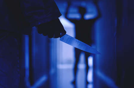 Close up of Hand with knife following young terrified man, Bandit is holding a knife in hand. Threat...