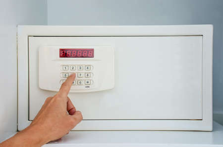 Hand putting password in the safety money box in hotel room or home, Safety box or modern electronic...