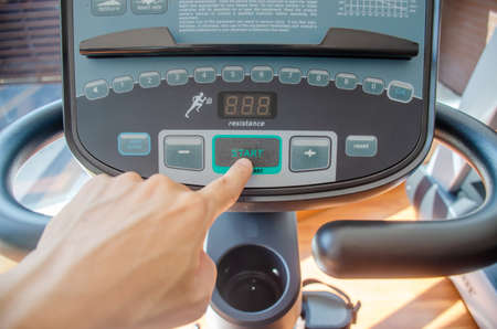 Selective focus "start", Male hand pushes green start button on a threadmill control panel in the gymの写真素材