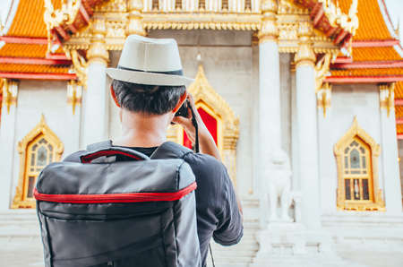 Asian man tourist taking photo with camera at Wat Benchamabophit Dusitvanaram Bangkok Thailand. Travelers take pictures with DSLR cameras. Asia tourist, Thailand.の写真素材