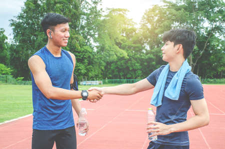 Two friends runners greeting each other handshaking at the stadium running track - Runners shake hands in sign of mutual respect in life and in sport - Concept of friendshipの写真素材