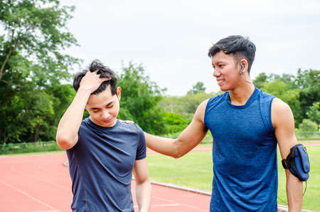Friends comforting sad young male runner after losing game outdoors at stadiumの写真素材