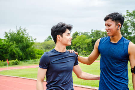 Friends comforting sad young male runner after losing game outdoors at stadiumの写真素材