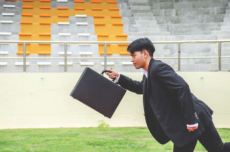 Picture of young businessman holding a briefcase and sprinting on the lanes of a track, Competition concept.の写真素材