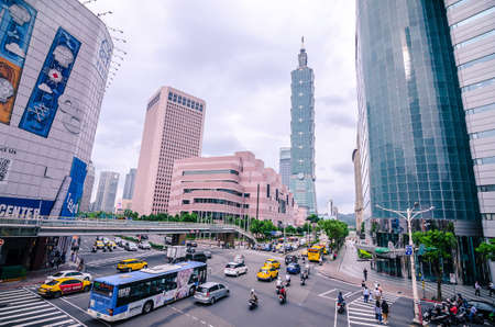 Taipei, Taiwan - May 15, 2019: View of a busy street corner in Downtown Taipei City at rush hour with cars & buses dashing by, Taipei 101 Tower & World Trade Center Building in Xinyi Financial District & people passing on crosswalkのeditorial素材