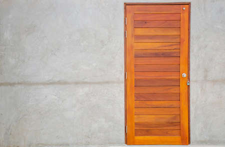 brown wooden door embedded in a gray concrete wallの写真素材