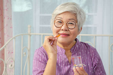 age, medicine, health care and people concept - happy senior woman holding medicine in his hand  at home or hospital officeの写真素材