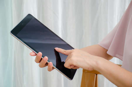 Cropped shot of female hands working with a tablet computer at home, tablet with copy spaceの写真素材
