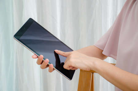 Cropped shot of female hands working with a tablet computer at home, tablet with copy spaceの写真素材