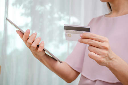Female hands holding discount credit card in hand paying for shopping online at tablet, Youth casual lifestyleの写真素材