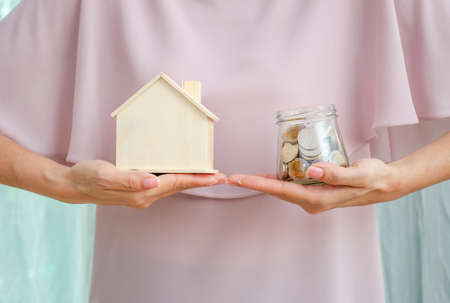 Loan or save for buy a house and real estate concept, Woman hand holding money  in glass jar and a...