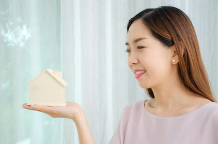 Architecture, building, construction, real estate and property concept, Happy woman hands holding wood house close upの写真素材