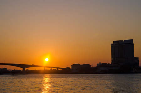 Silhouette of Bangkok Transportation at Sunset with Building along the river