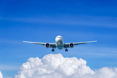 Passenger plane in flight. Aircraft fly high in the sky above the clouds. Front view of airplane.の写真素材