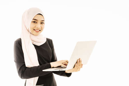 Portrait of beautiful asian muslim woman smiling using laptop computer on white background, Concept for social media, register, enter, membership, sign-in, socializeの写真素材