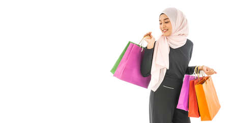 Portrait of beautiful asian muslim woman in a black hijab holding multi-colored shopping bags in her hand religion Islam shopping on white backgroundの写真素材