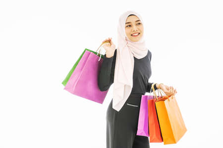 Portrait of beautiful asian muslim woman in a black hijab holding multi-colored shopping bags in her hand religion Islam shopping on white backgroundの写真素材