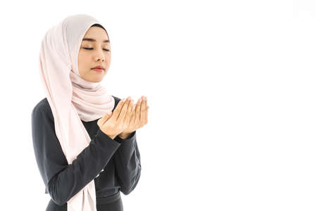 Portrait of beautiful asian muslim woman in a black hijab praying for Allah, muslim God, Praying hands, muslim meditating pray, muslim prayer, isolated over white backgroundの写真素材