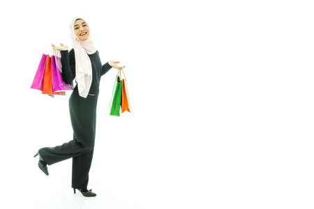 Portrait of beautiful asian muslim woman in a black hijab holding multi-colored shopping bags in her hand religion Islam shopping on white backgroundの写真素材