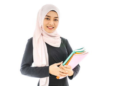 Portrait of smiley beautiful young muslim woman student wearing Hijab holding colorful book on white background, Education exam preparing conceptの写真素材