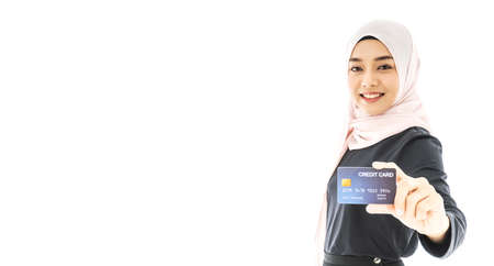 Portrait of beautiful asian muslim woman in a black hijab holding credit card with happy and smiling isolate on white background. Business and finance credit card concept.の写真素材
