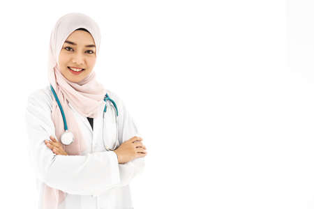 Portrait of beautiful asian muslim woman doctor smiling with folded arms isolated over white backgroundの写真素材