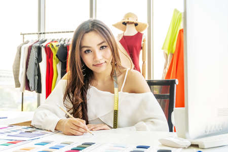 Asian woman designer are thinking and drawing something on paper for customers order items at the...