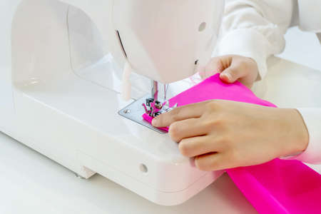 Fashion designer stylish showroom concept. Close up hand women is sewing on the sewing machine in the studio, the tailor creates collection of outfits, new designの写真素材