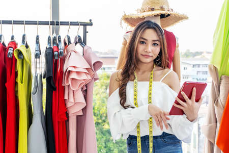 Woman fashion designer working in clothing shop studio and using tablet computer in the studio. Tailor sewing. People lifestyle conceptの写真素材