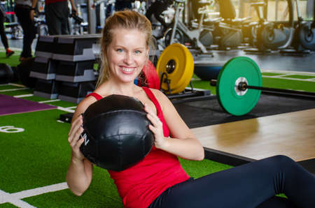 Sporty girls smiling exercises with fitness ball for six pack in the gym.の写真素材