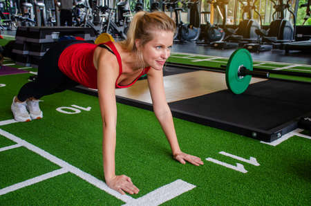Close up young woman doing push-ups at the gym. Muscular female doing pushups on exercise at gym, Fitness exercise and healthy concept.の写真素材